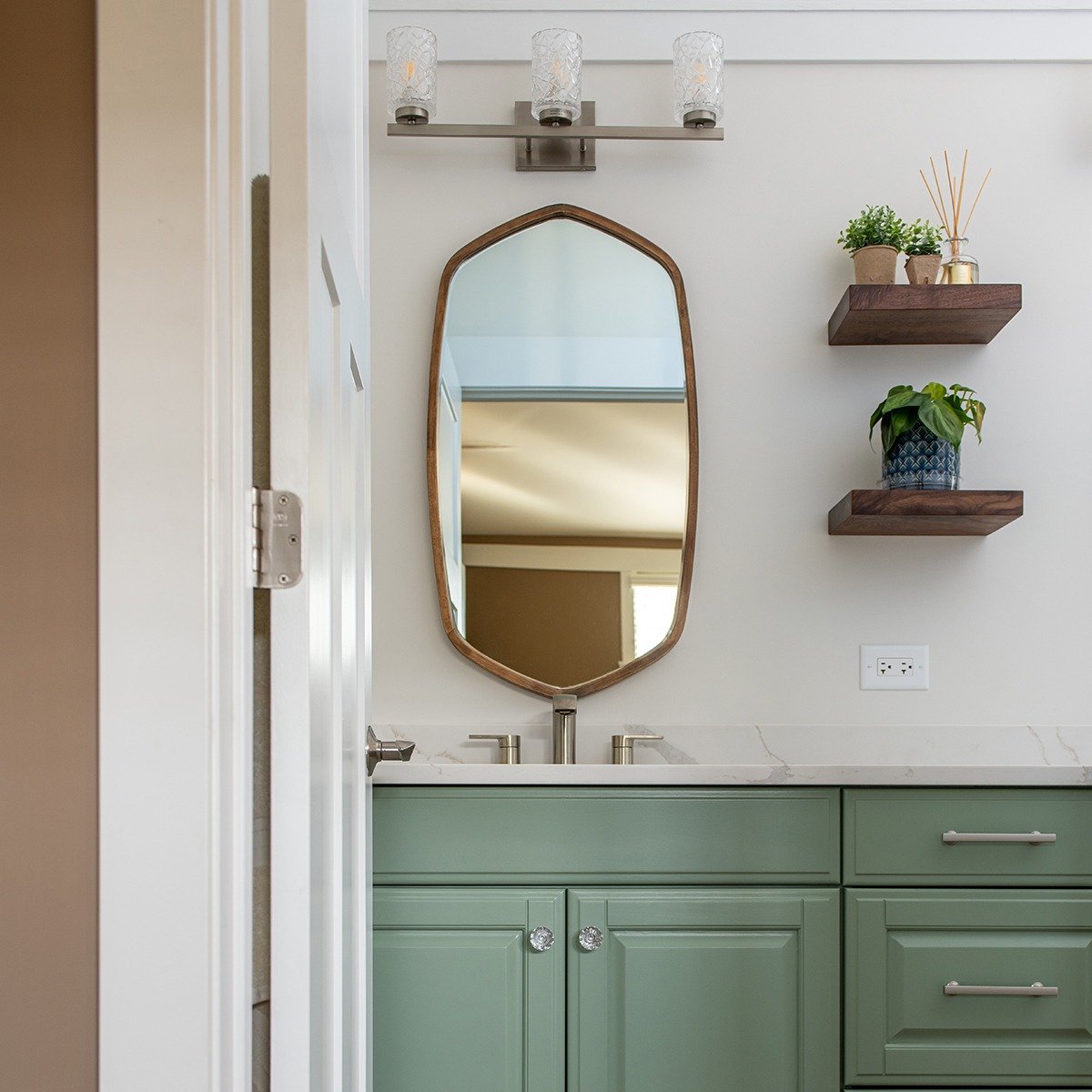 Primary bathroom with unique framed mirror, repainted vanity cabinet, wooden wall shelves and modern fixtures.