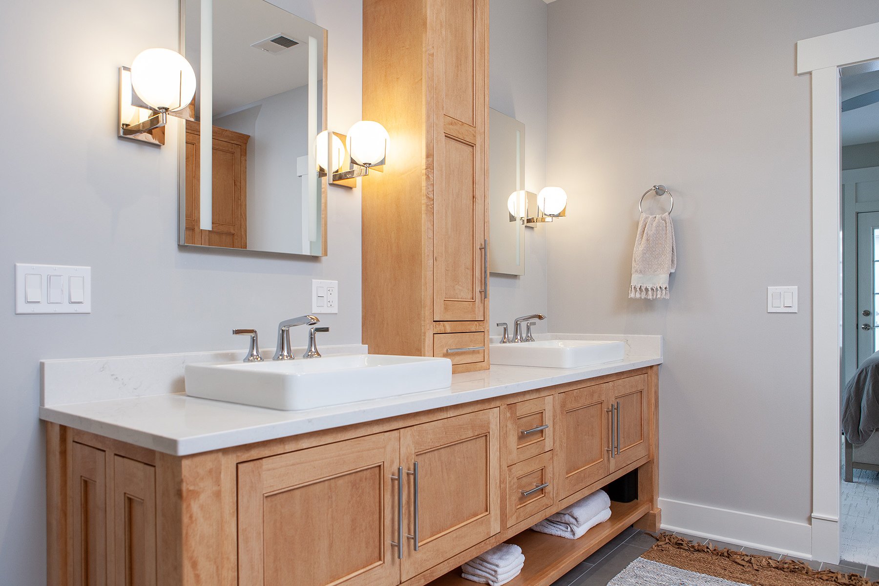 Primary bathroom with double sinks, champagne bronze hardware, white countertops and gold wall sconces. 