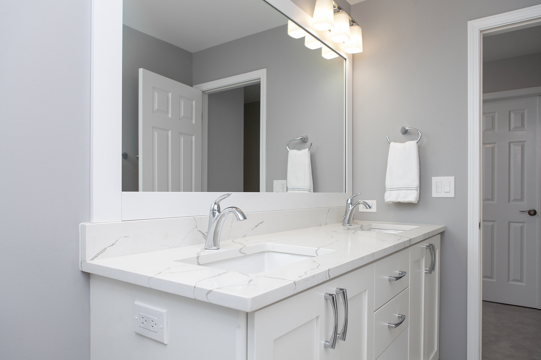 remodeled home bathroom with white cabinetry, light gray countertops and chrome finishes