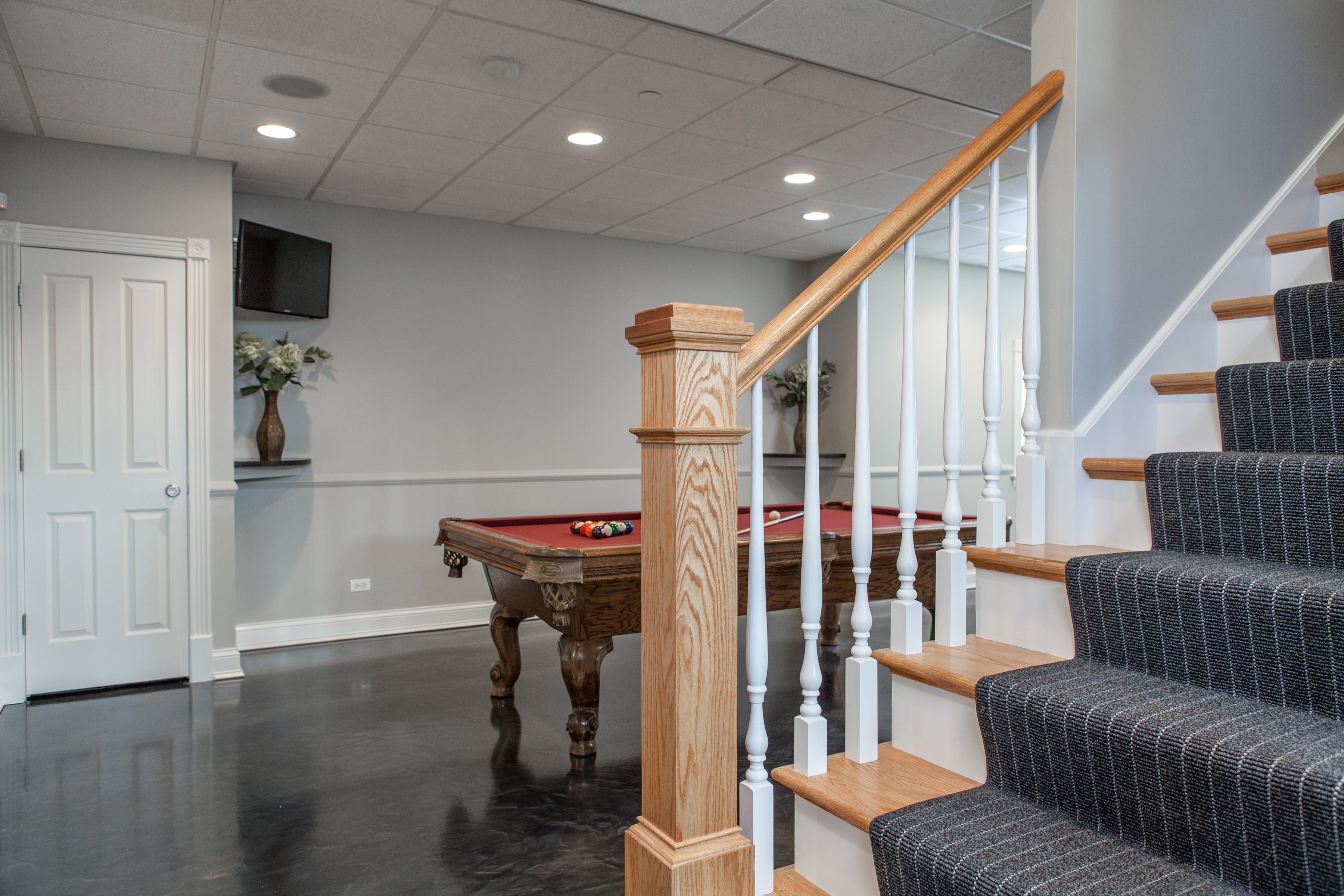 staircase leading down to remodeled basement with pool table in background