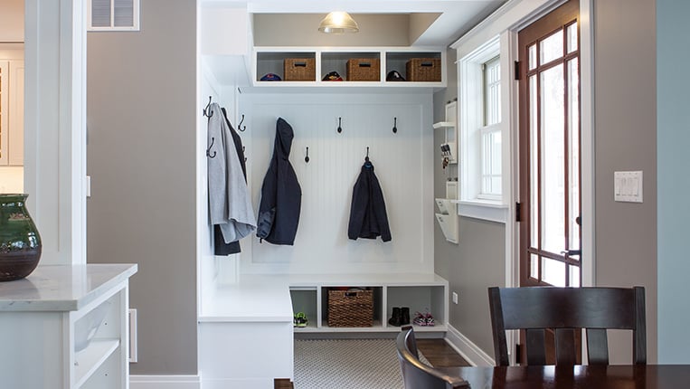 Beautiful home mudroom off the front entryway with white bead-board, coat hangers, and storage nooks.