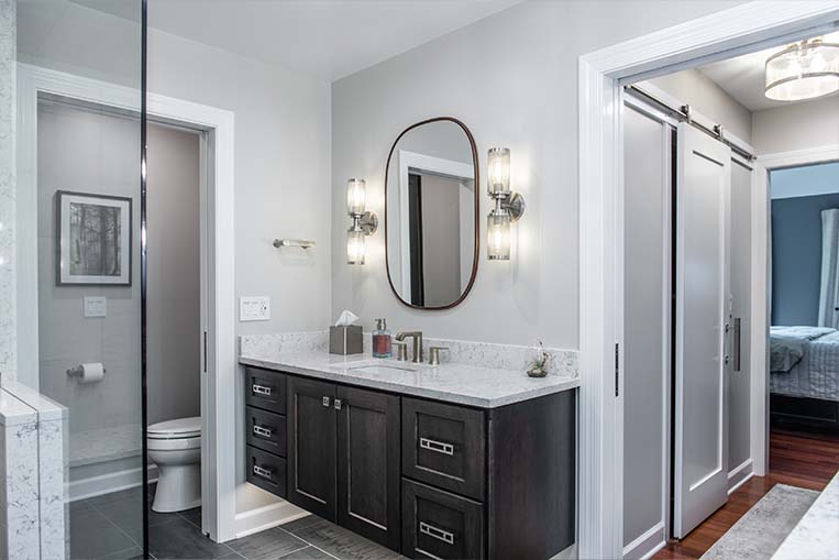 Modern bathroom with rounded wall mirror, double sconces and floating vanity.